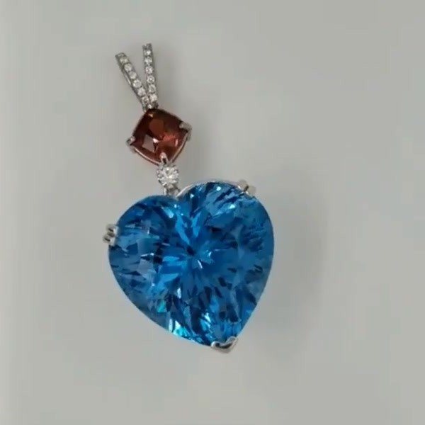 80 carat heart-shaped Swiss blue topaz pendant with a red Malaya garnet